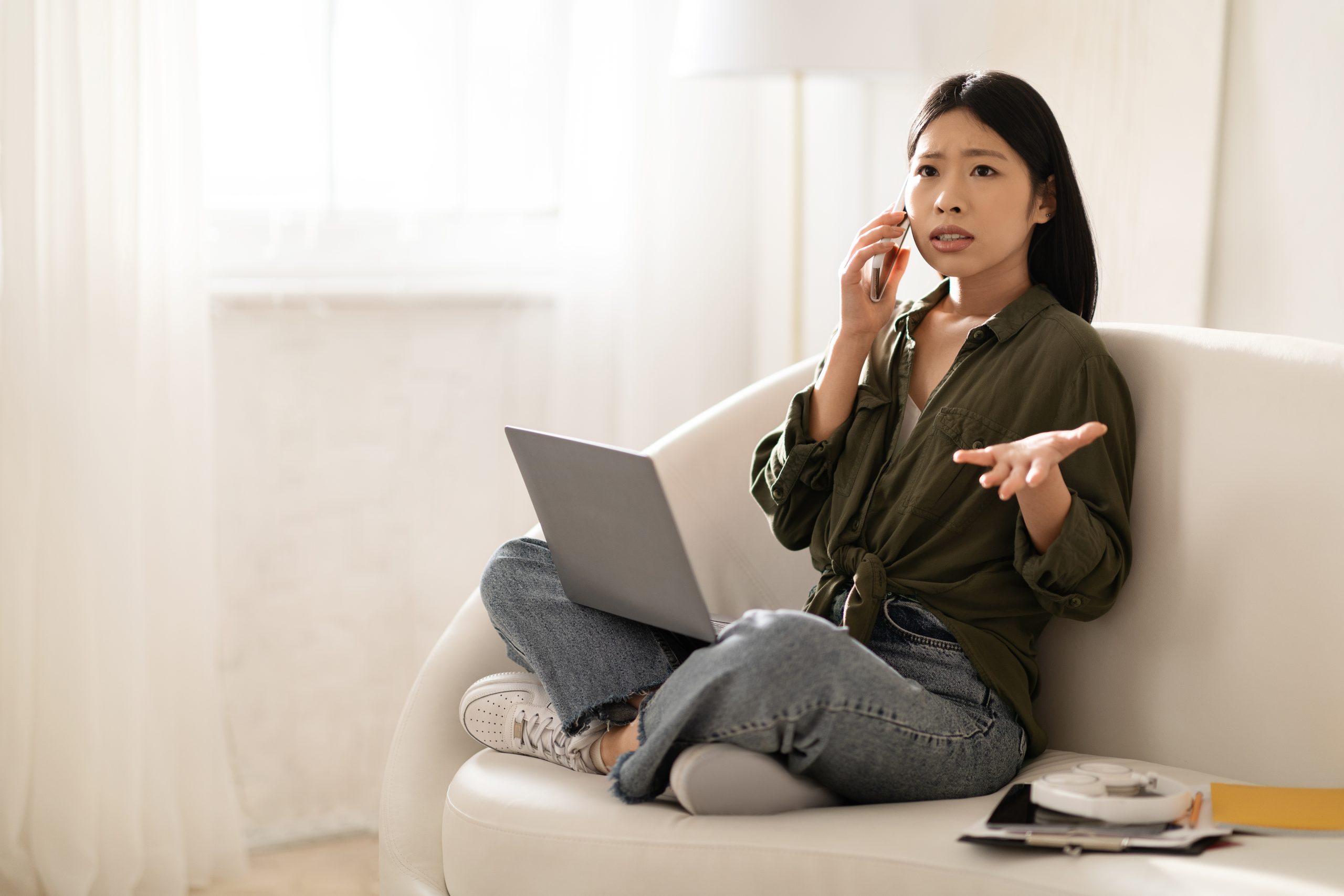 Angry asian businesswoman have phone conversation, home interior frustrated woman on the phone