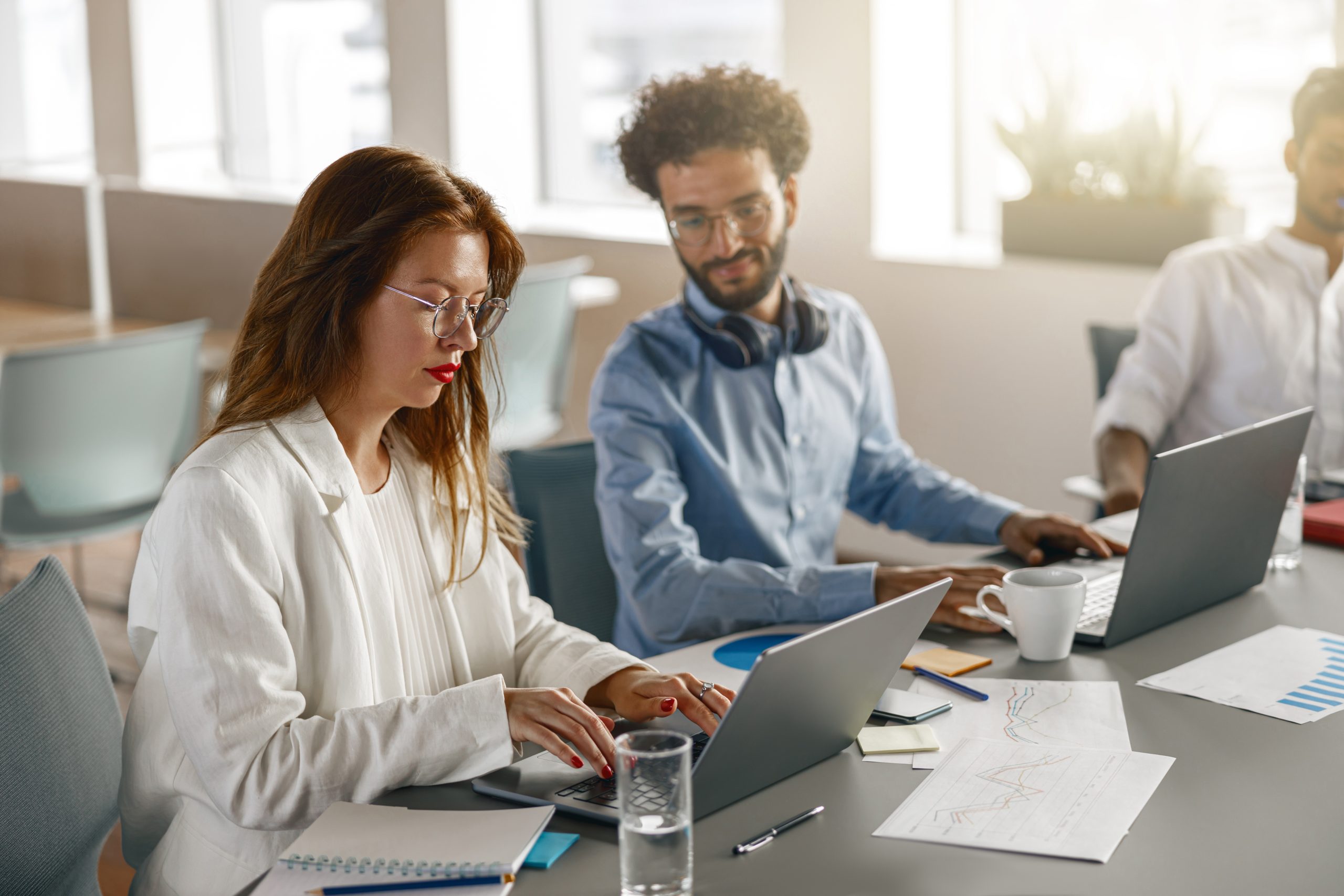 Diverse coworkers analyzing sales report while working together in office. Blurred background