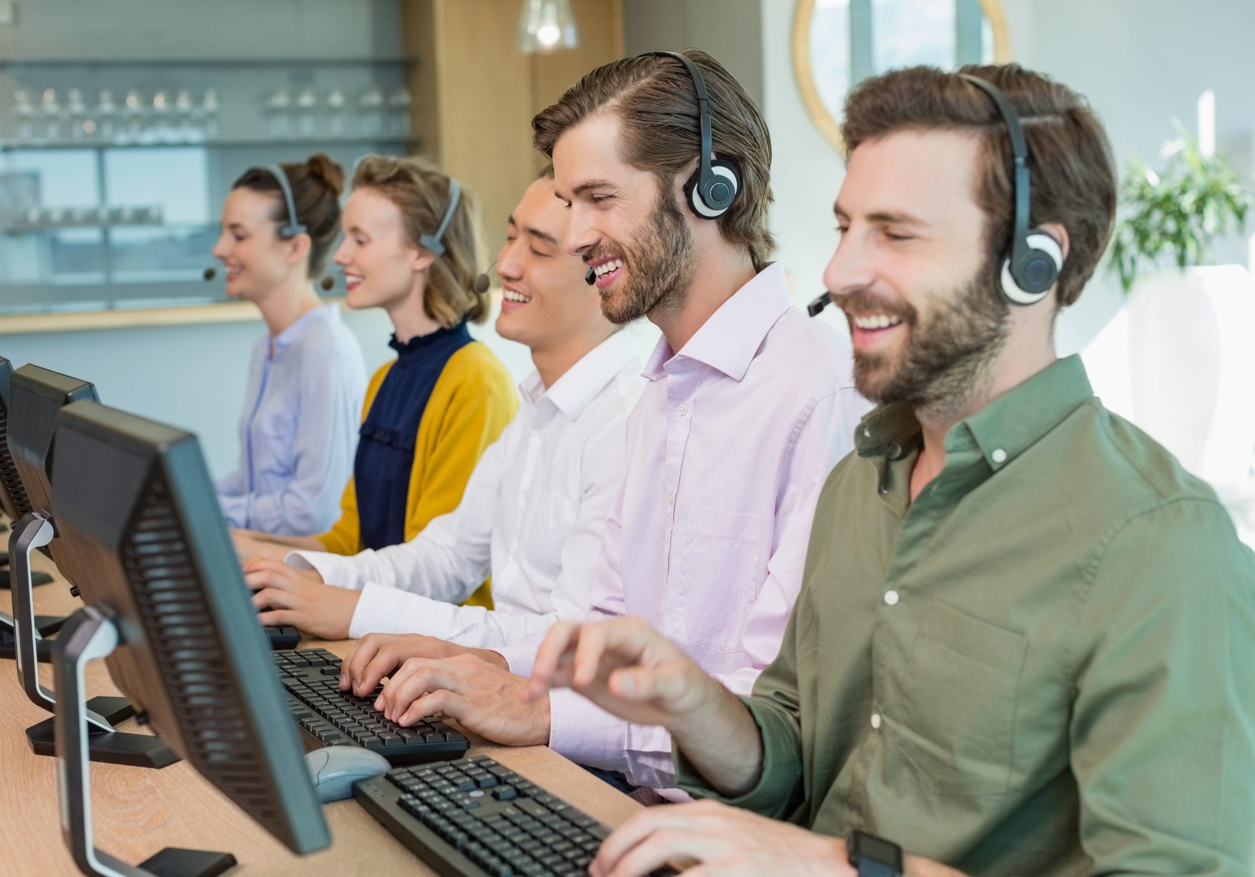 Customer service executives working in call center Row of smiling people at a call center